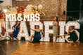 Load image into Gallery viewer, Mr & Mrs Harris wedding light up letters with group of bridesmaids