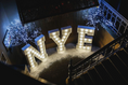 Load image into Gallery viewer, Decorative lights spelling 'NYE' on a staircase with festive lights in the background.