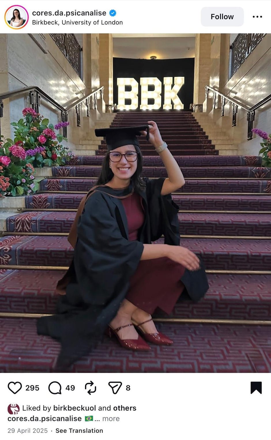 Graduate posing on a staircase with 'BBK' sign in the background