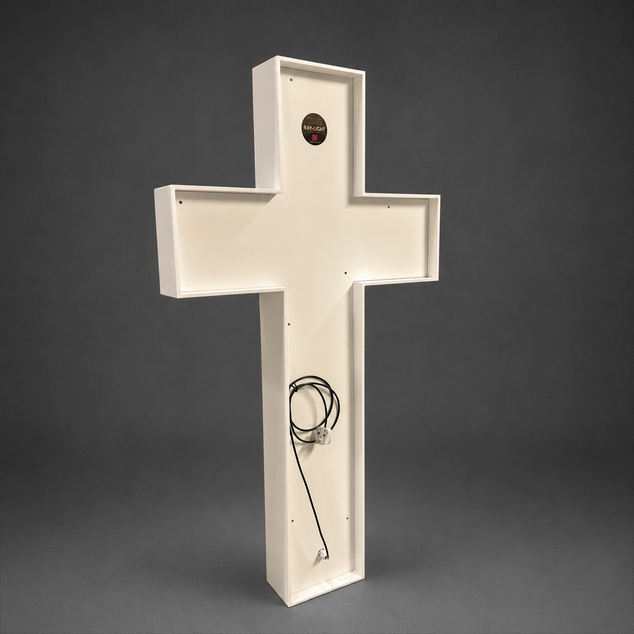 White cross-shaped object with a cable on a gray background