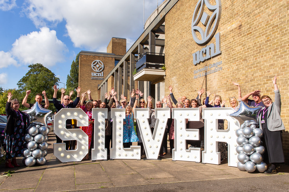 Illuminated SILVER light up letters outside UCNL university building with staff celebrating anniversary event